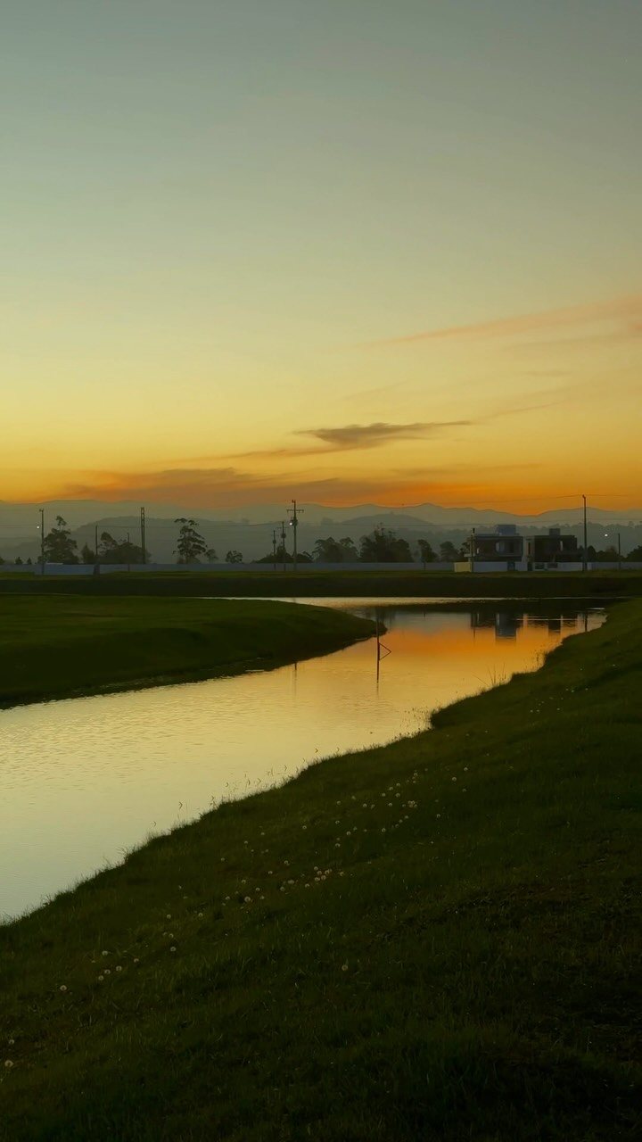 Lago ao pôr do sol, com margens gramadas